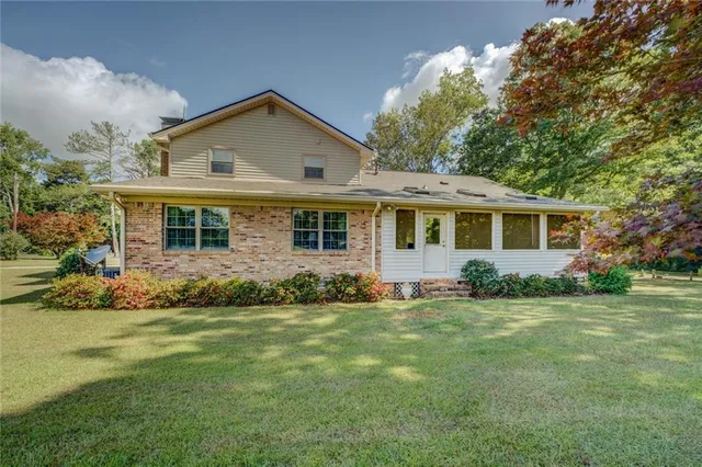 a view of a big house with a big yard and large trees