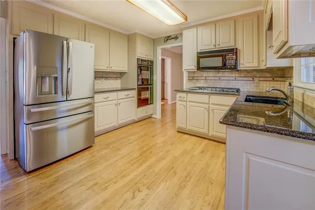 a kitchen with stainless steel appliances granite countertop a refrigerator and a stove top oven