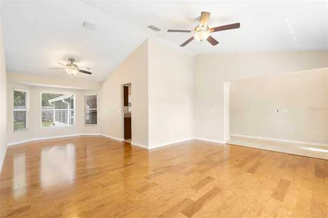 a view of an empty room with windows and ceiling fan view