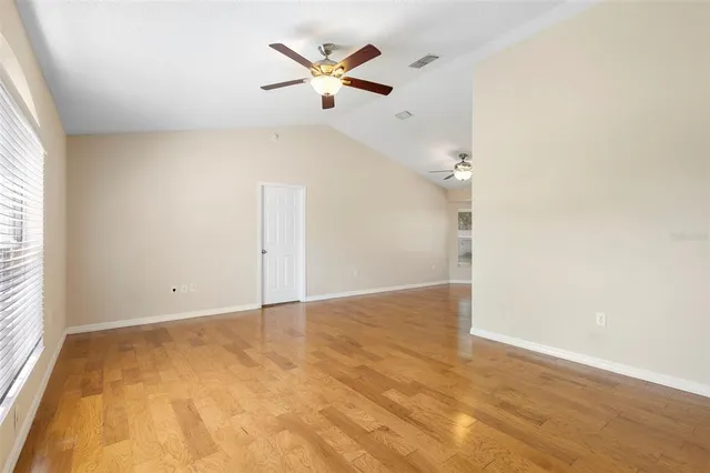 an empty room with a ceiling fan and wooden floor