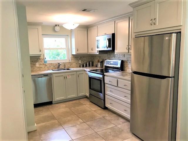244 Hilltop Drive Santa Rosa Beach, FL 32459 - Photo 8 of 20 a kitchen with white cabinets stainless steel appliances and a window