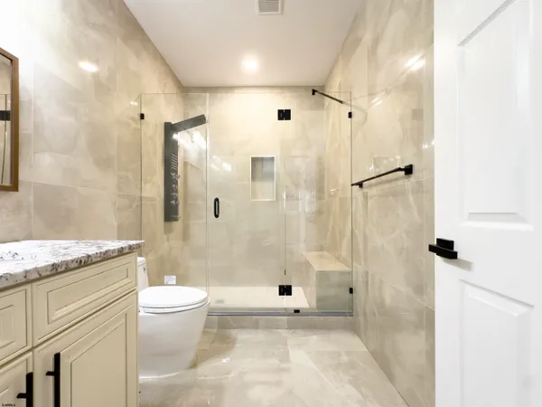 a bathroom with a granite countertop sink a toilet and shower