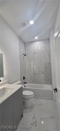 a bathroom with a bathtub shower sink mirror and toilet