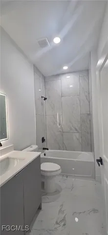 a bathroom with a bathtub shower sink mirror and toilet