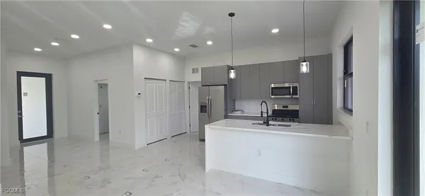 a room with kitchen island a sink and a refrigerator