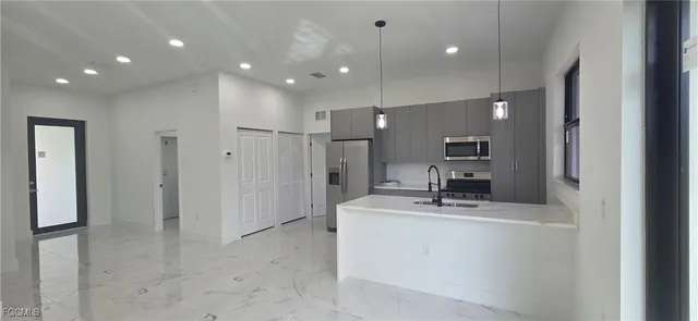 a room with kitchen island a sink and a refrigerator