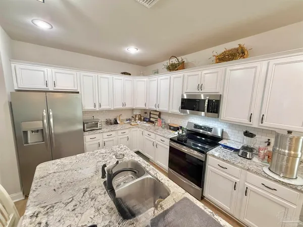 a kitchen with granite countertop a sink stainless steel appliances and white cabinets