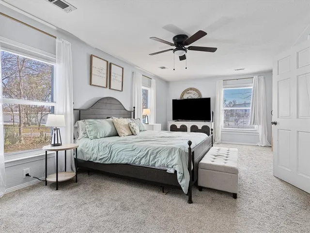 a spacious bedroom with a bed and a flat screen tv