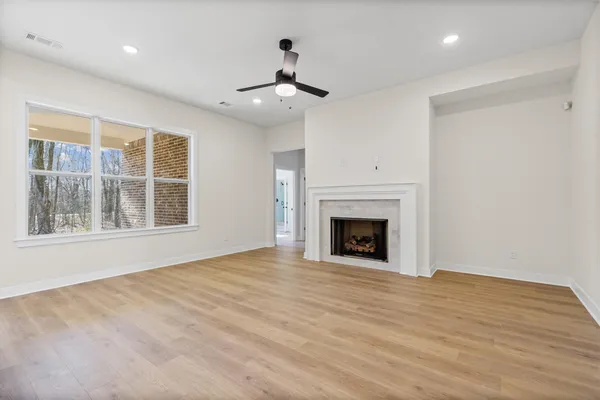 a view of an empty room with wooden floor fireplace and a window