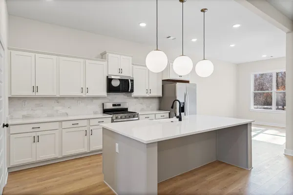 a large white kitchen with a sink stainless steel appliances and cabinets