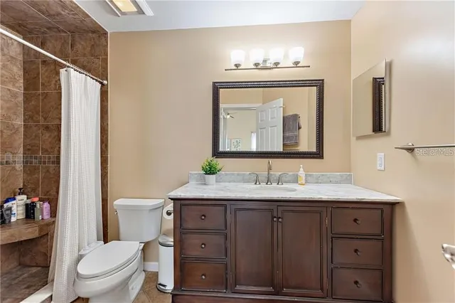 a bathroom with a granite countertop toilet sink and mirror