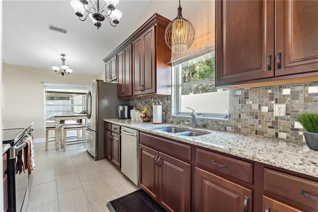 a kitchen with granite countertop stainless steel appliances a sink counter space cabinets and a window