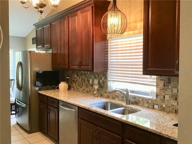 a kitchen with granite countertop stainless steel appliances a sink and refrigerator