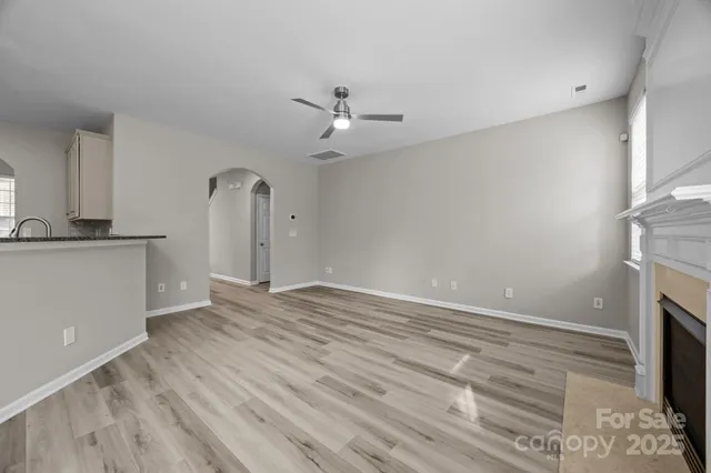 a view of an empty room with wooden floor fireplace and a window
