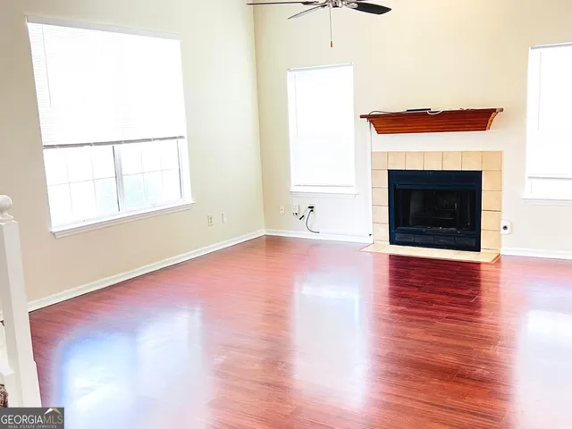 an empty room with wooden floor fireplace and windows