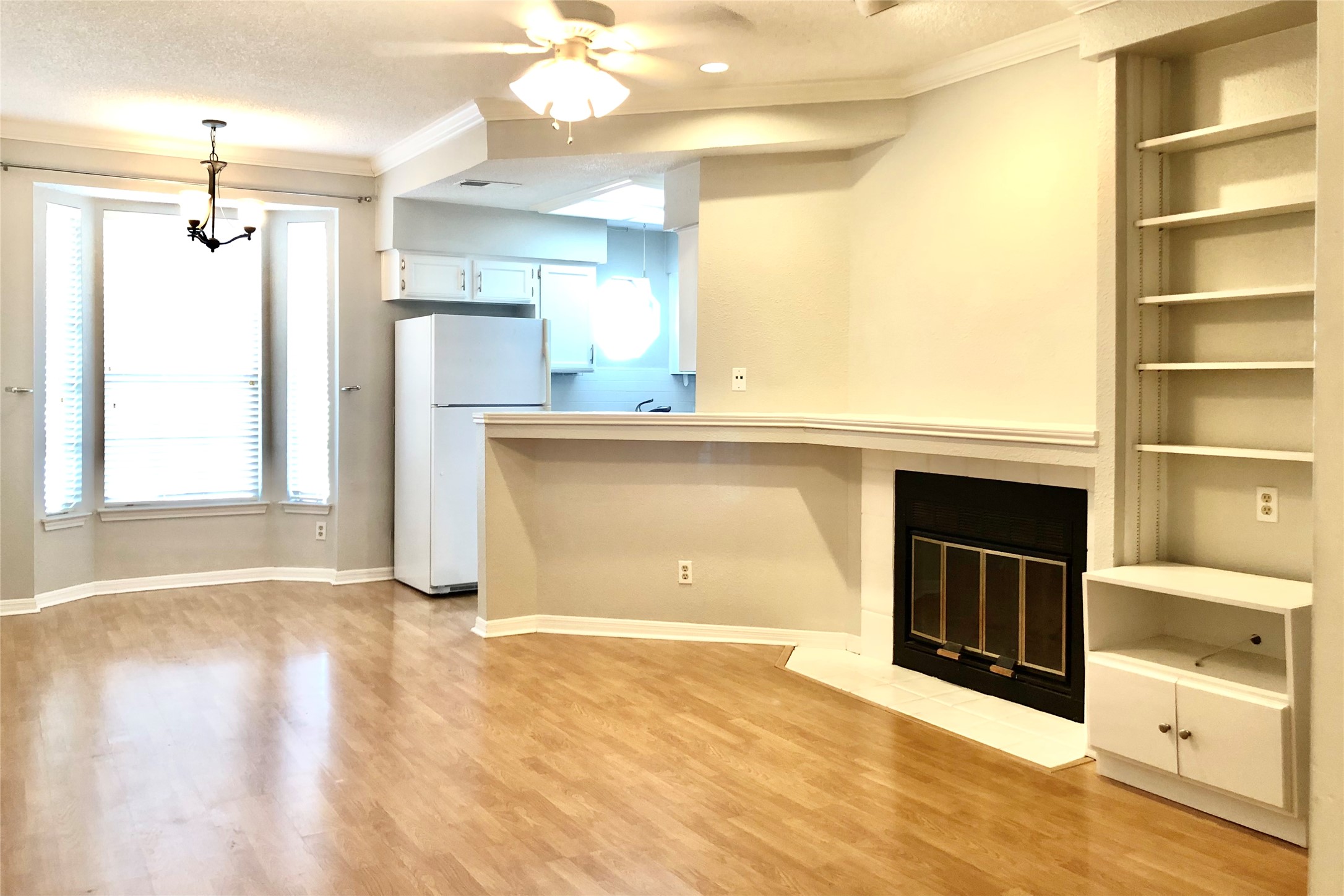 3111 Tom Green Street, Unit 204 Austin, TX 78705 - Photo 2 of 9 Unfurnished living room with crown molding, a ceiling fan, a fireplace with flush hearth, light wood-style floors, and a textured ceiling
