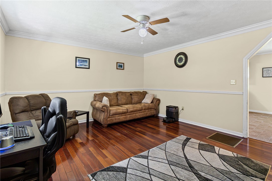 322 Tribble Street Honea Path, SC 29654 - Photo 6 of 35 Warm hardwood floors and classic crown molding anchor this versatile living space.
