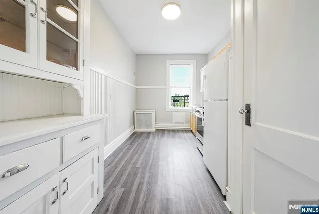 a view of a kitchen with white cabinets and wooden floor