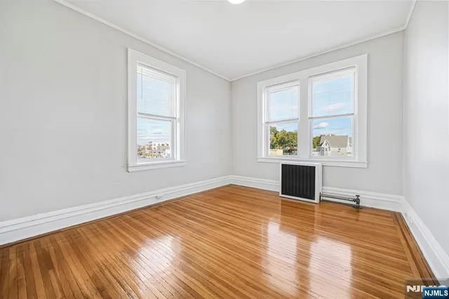 an empty room with wooden floor cabinet and windows