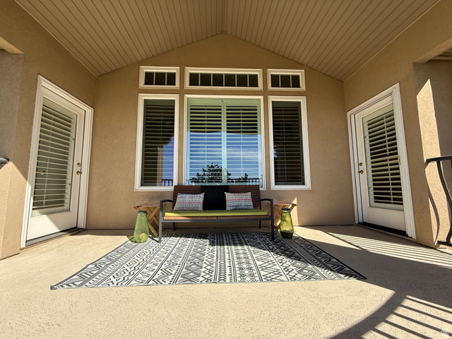 1562 Fairway Ridge Road Draper, UT 84020 - Photo 22 of 60 Covered patio featuring an angled wood-finish ceiling, textured exterior walls, multiple windows with plantation shutters, and two glass-paneled doors with internal blinds