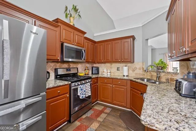 a kitchen with stainless steel appliances granite countertop a stove top oven a sink dishwasher a refrigerator and a microwave