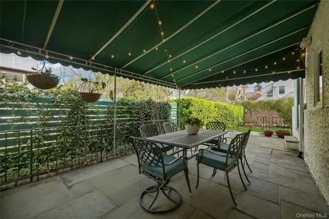 a patio with table and chairs and potted plants
