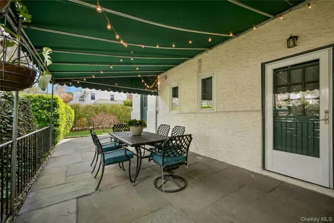 a patio with a table and chairs and potted plants
