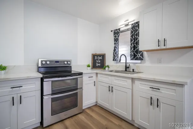 a view of kitchen with stainless steel appliances wooden floor and window