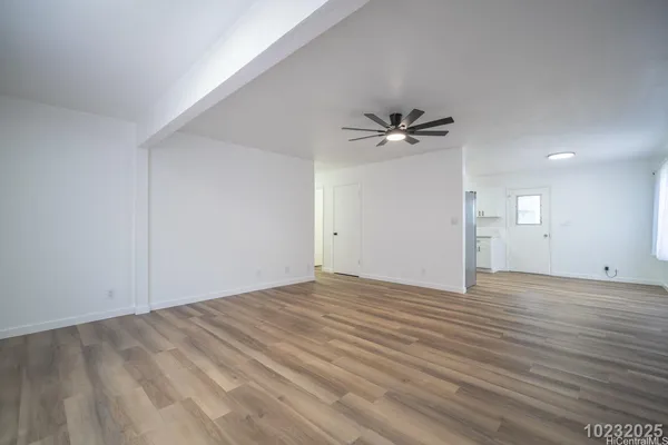a view of an empty room with wooden floor and a window