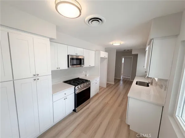 a kitchen with granite countertop a sink a stove top oven and wooden floor