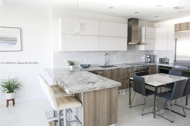 a kitchen with granite countertop a table chairs stove top oven and cabinets