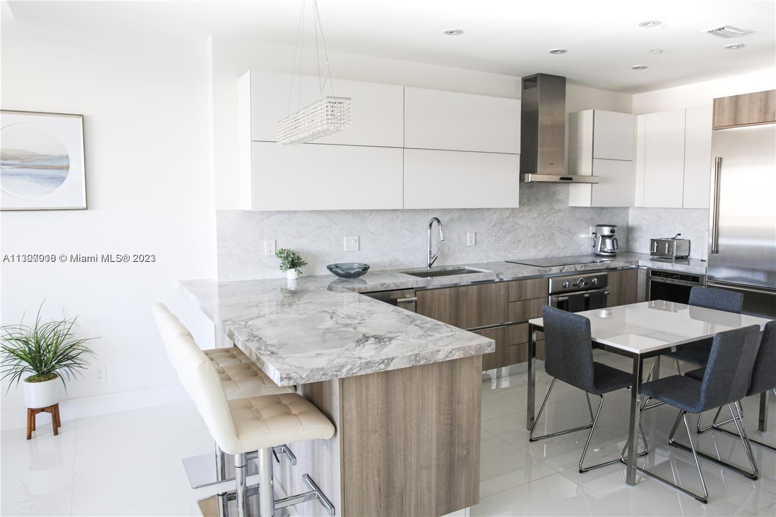 100 Lincoln Road, Unit 1643 Miami Beach, FL 33139 - Photo 2 of 7 a kitchen with granite countertop a table chairs stove top oven and cabinets