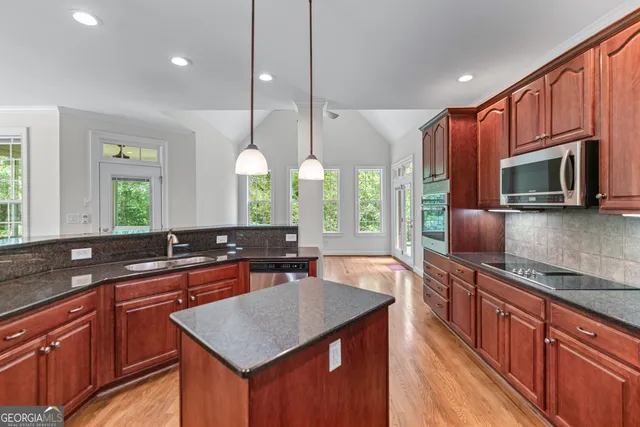 a kitchen with stainless steel appliances granite countertop a sink a stove counter space and cabinets