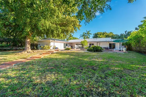 a view of house with a big yard and large trees