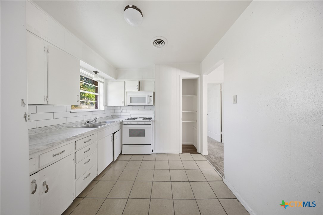 1311 Missouri Avenue Killeen, TX 76541 - Photo 11 of 29 a kitchen with granite countertop white cabinets and white appliances