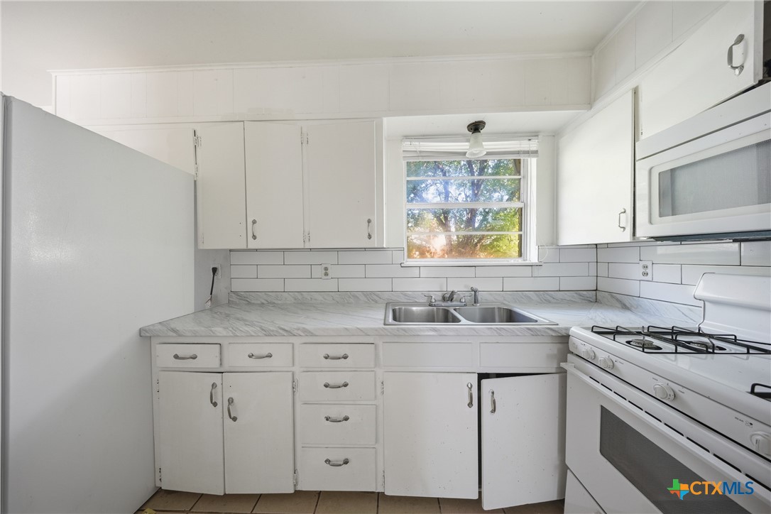 1311 Missouri Avenue Killeen, TX 76541 - Photo 12 of 29 a kitchen with cabinets appliances a sink and a window