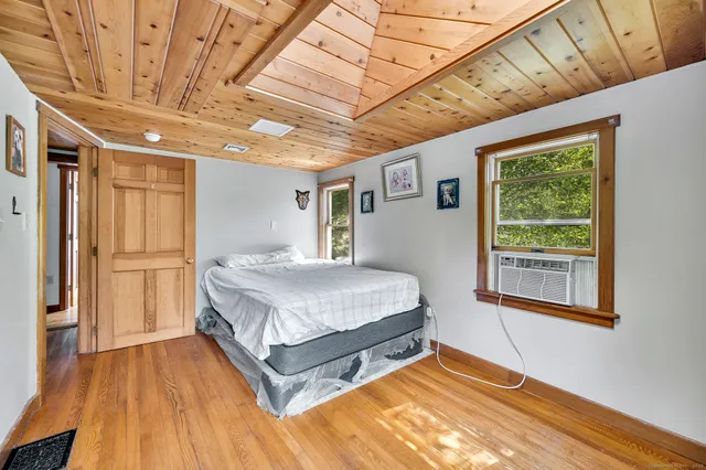 a spacious bedroom with a bed and wooden floor