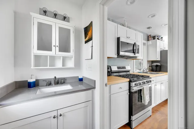 a kitchen with stainless steel appliances granite countertop grey cabinets a stove a sink and a refrigerator