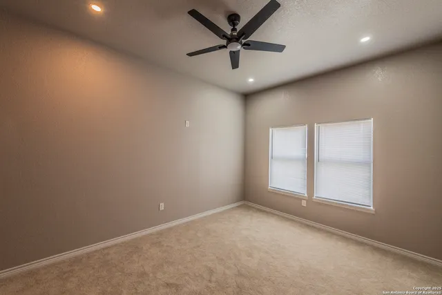 an empty room with a ceiling fan and window