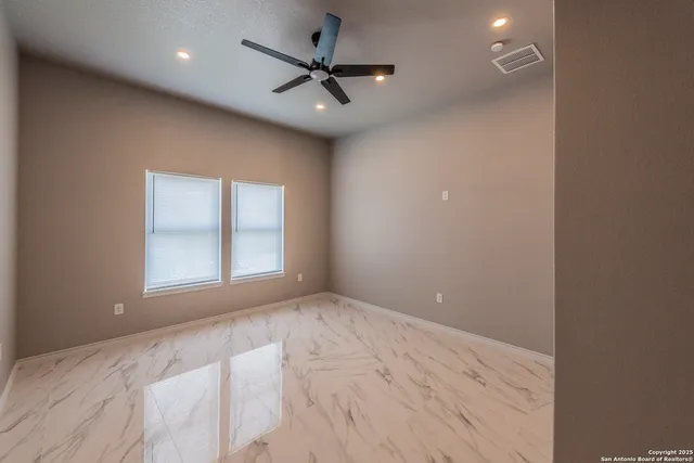 an empty room with a ceiling fan and window