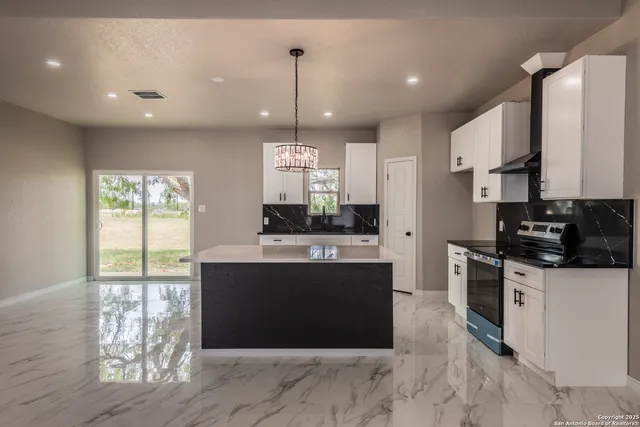 a large kitchen with stainless steel appliances granite countertop a stove a refrigerator a sink dishwasher and a dining table with wooden floor