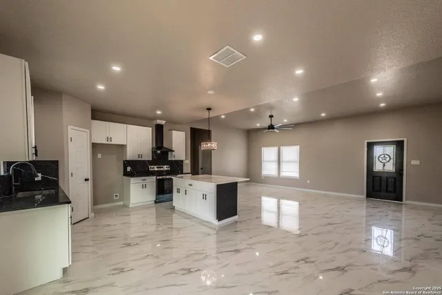 a kitchen with stainless steel appliances kitchen island granite countertop a stove a refrigerator a sink a refrigerator and white cabinets with wooden floor