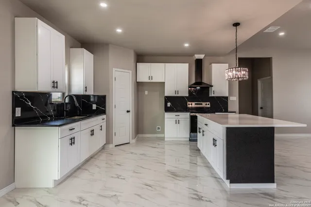 a kitchen with stainless steel appliances kitchen island granite countertop a refrigerator a sink a stove and oven with wooden floor