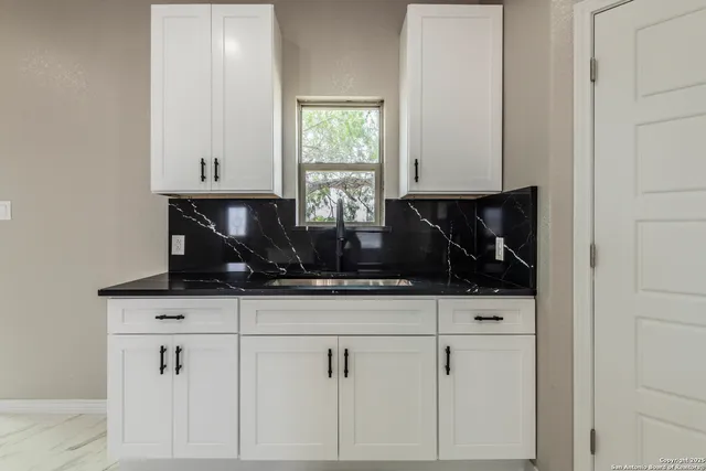 a kitchen with white cabinets and window