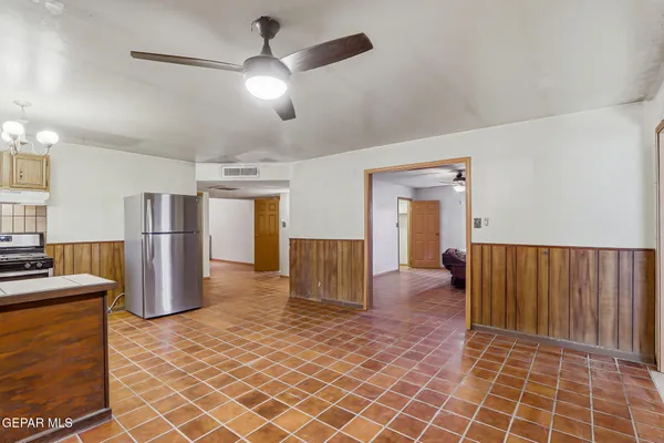 an open kitchen with refrigerator and ceiling fan
