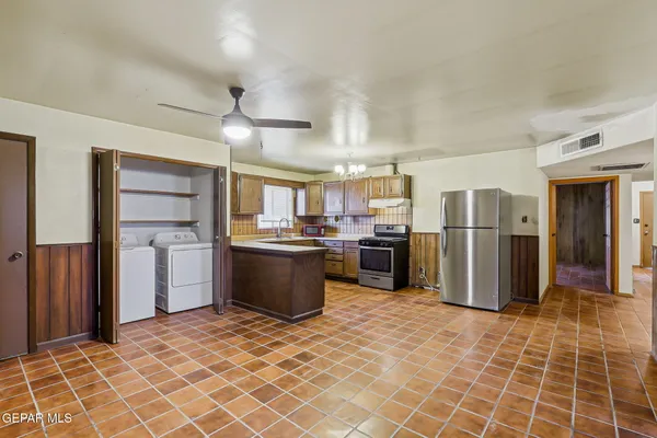 a kitchen with stainless steel appliances granite countertop a refrigerator a sink a stove and a refrigerator