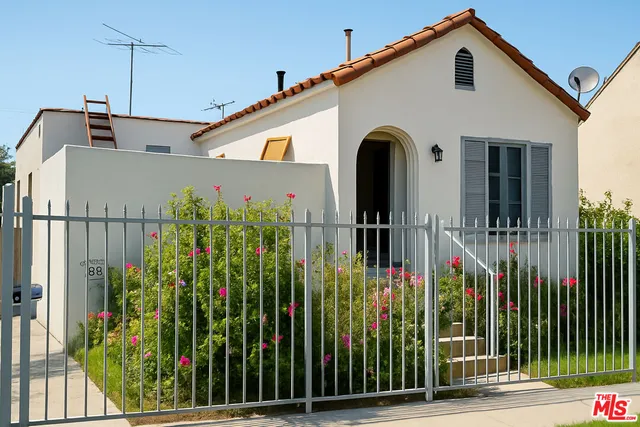 a view of a white house with a small yard and plants