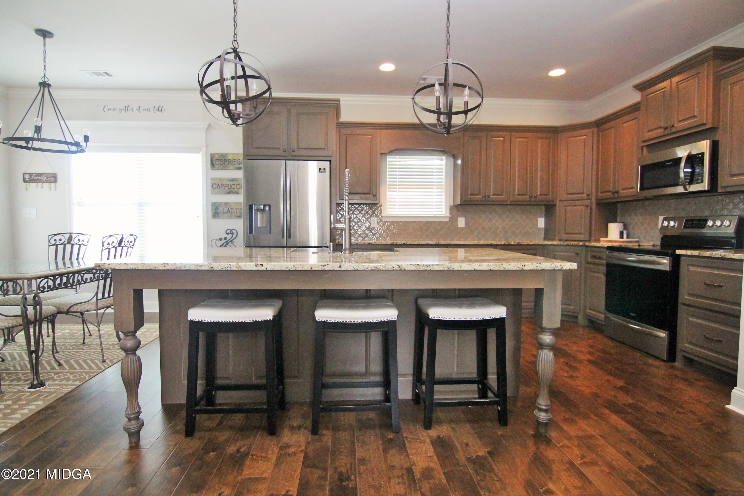 105 Timber Ridge Circle Byron, GA 31008 - Photo 12 of 28 a open kitchen with stainless steel appliances granite countertop a stove a sink dishwasher a dining table and chairs with wooden floor