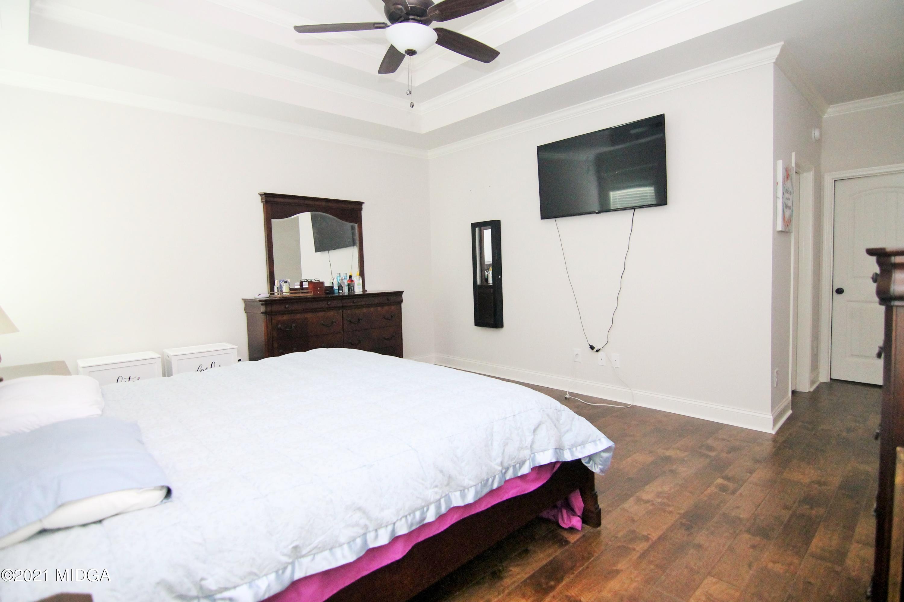 105 Timber Ridge Circle Byron, GA 31008 - Photo 14 of 28 a bedroom with a bed a flat screen tv and a chandelier