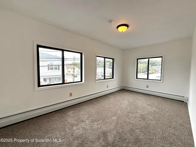 a view of an empty room with a window and a ceiling fan